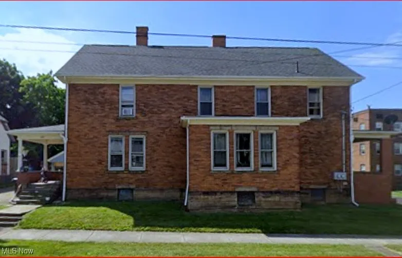 View of home's exterior with a chimney, a yard, and brick siding