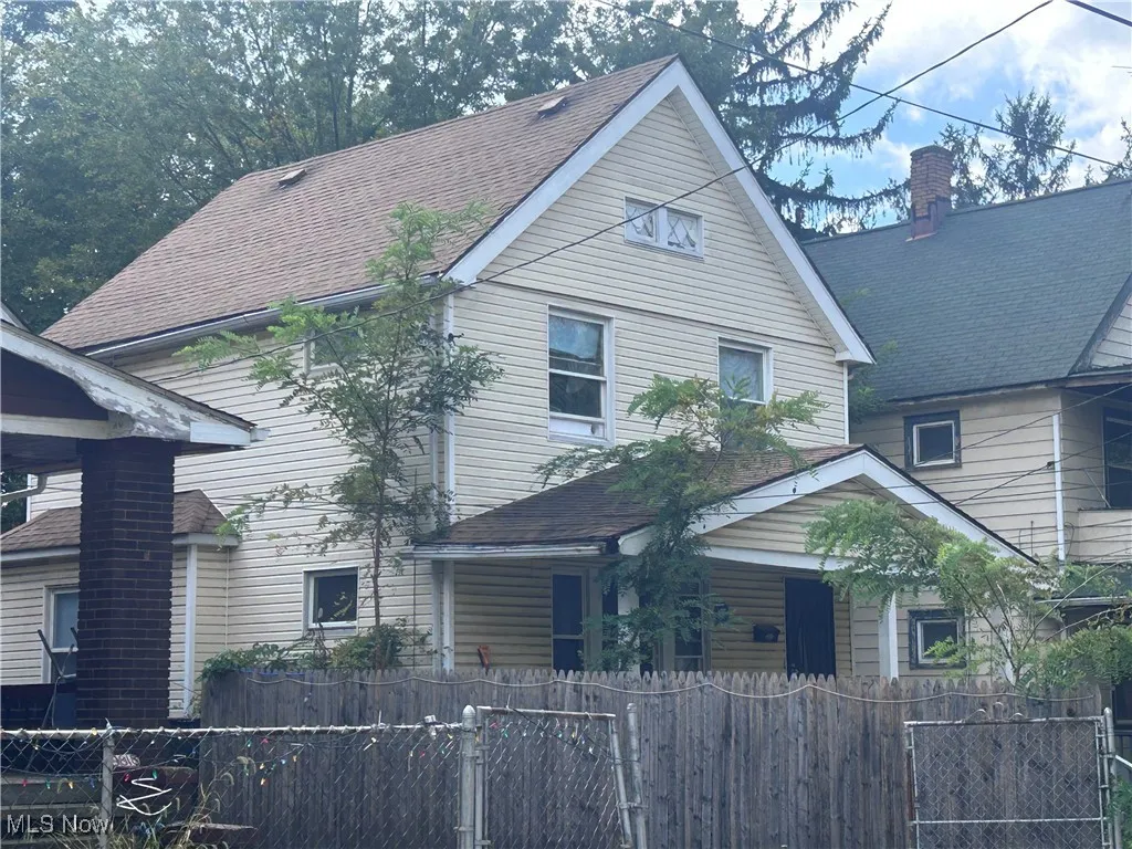 View of front of home with a fenced front yard, a gate, and roof with shingles