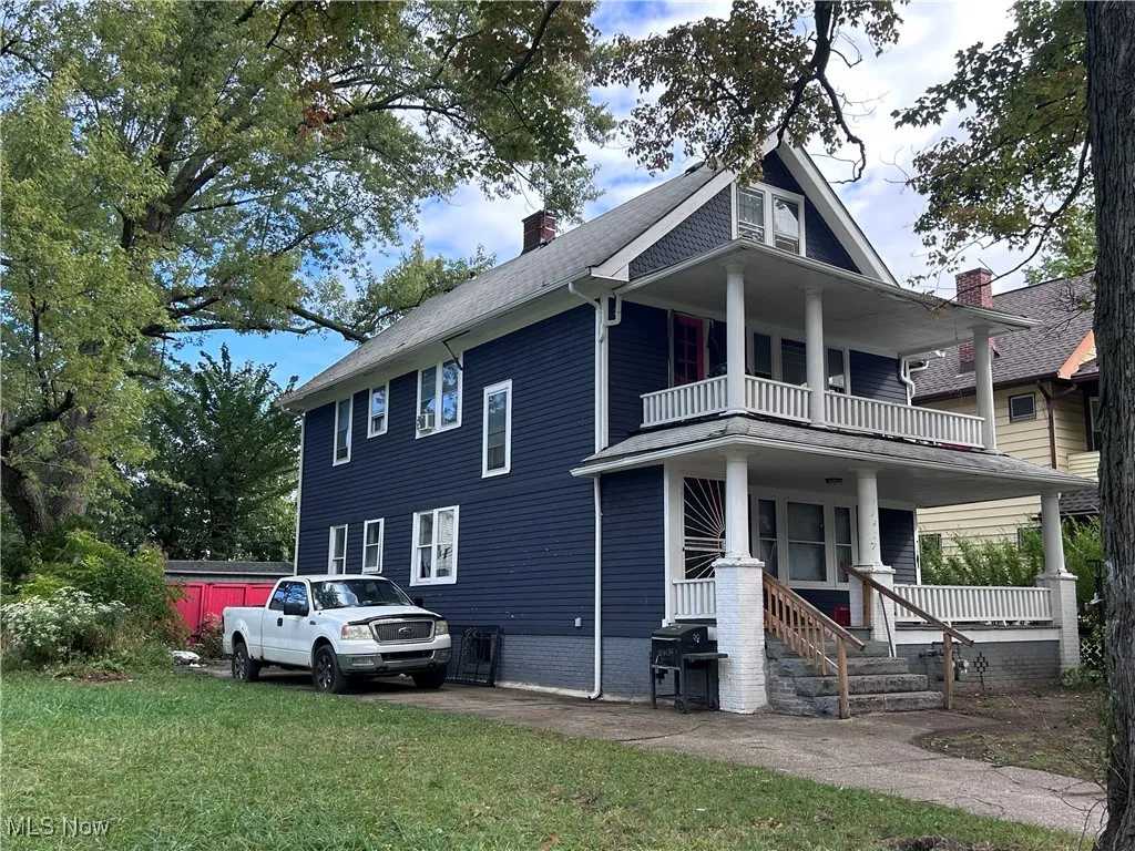 View of front facade with a porch, a front yard, a chimney, and a balcony