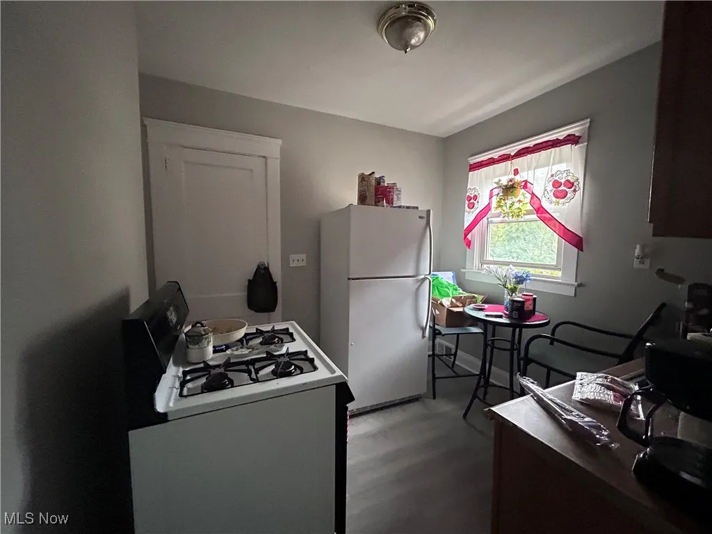 Kitchen with white appliances, a desk, and dark wood-type flooring