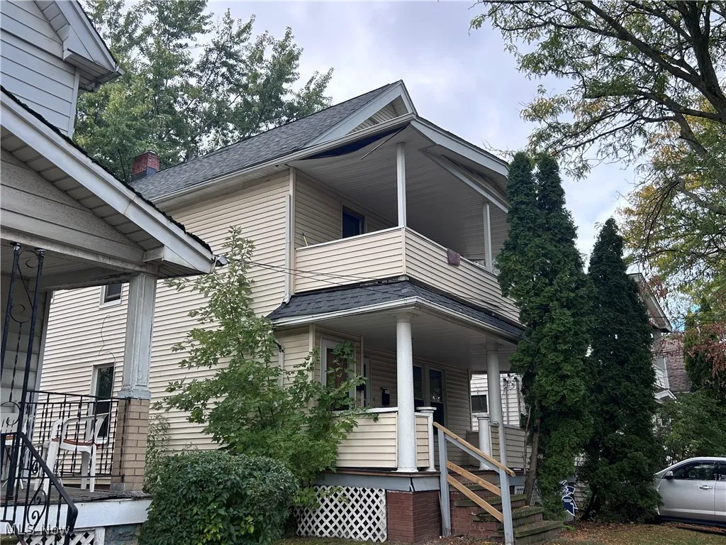 View of side of property featuring covered porch and roof with shingles