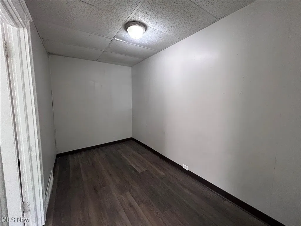 Spare room featuring dark wood-style flooring and a paneled ceiling