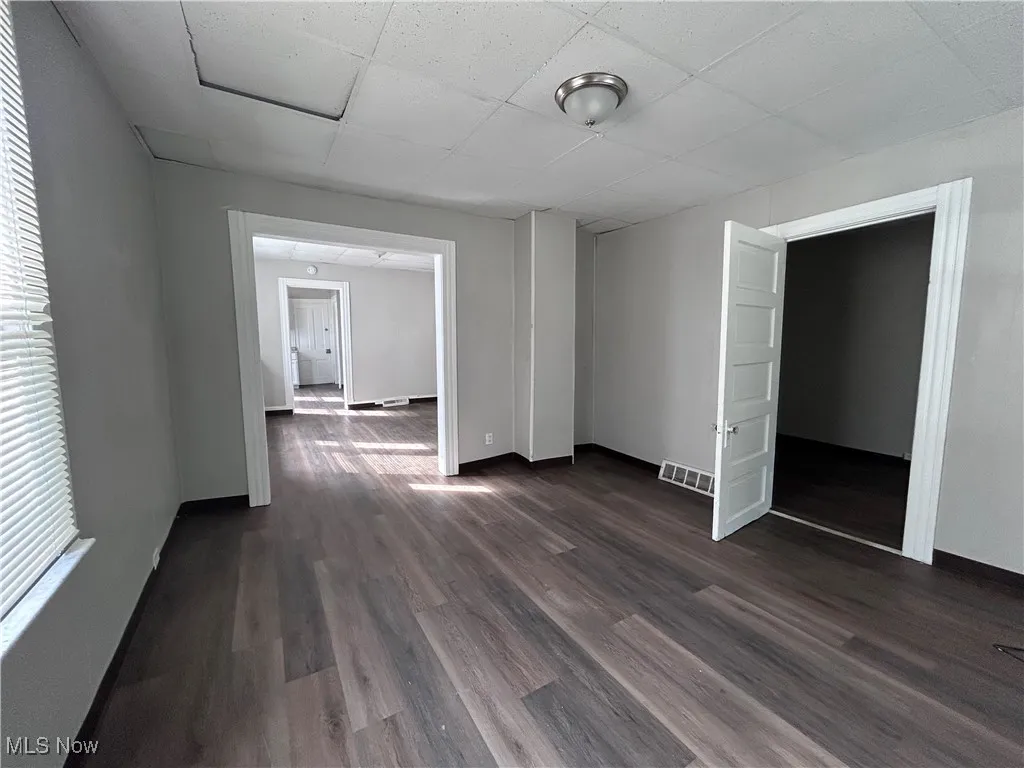 Spare room with dark wood-style flooring and a drop ceiling