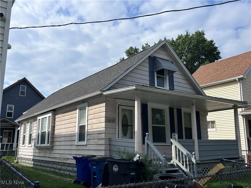 Bungalow featuring a fenced front yard, a shingled roof, and covered porch