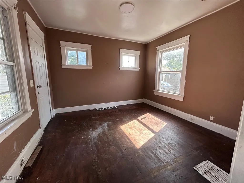 Empty room featuring dark wood-type flooring and healthy amount of natural light