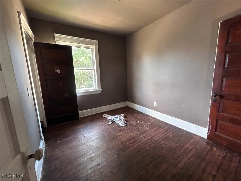 Unfurnished bedroom featuring dark wood-type flooring and baseboards