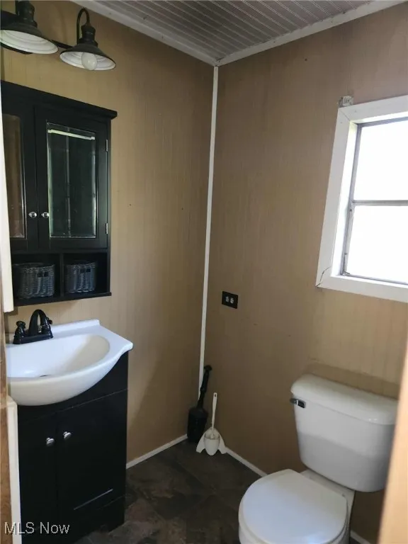 Half bath featuring vanity and wood walls