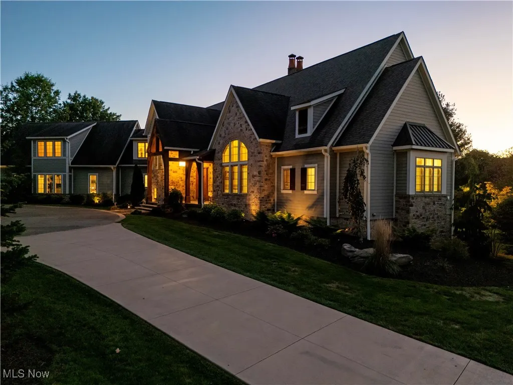 View of front of property with stone siding, a lawn, a chimney, and driveway