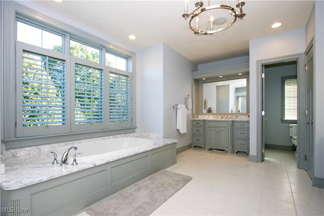 Bathroom featuring a garden tub, vanity, recessed lighting, a chandelier, and light tile patterned flooring