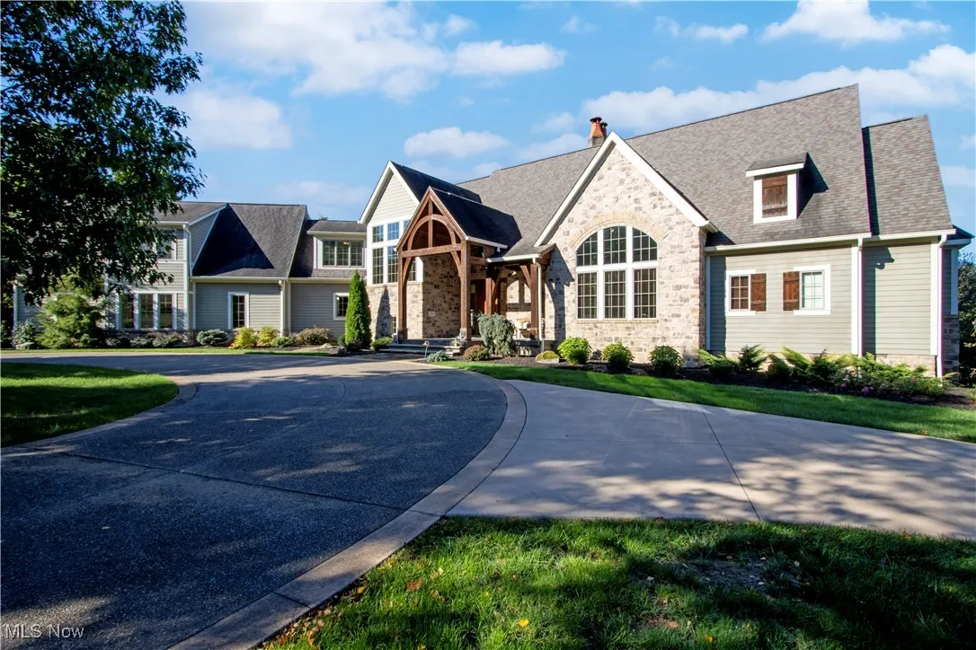 View of front facade featuring stone siding, a chimney, and a front yard