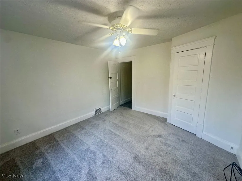 Unfurnished bedroom featuring a textured ceiling, carpet floors, and a ceiling fan