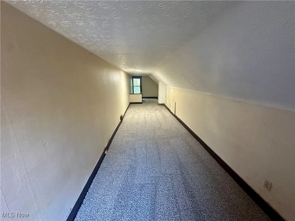 Bonus room featuring carpet flooring, a textured ceiling, and vaulted ceiling