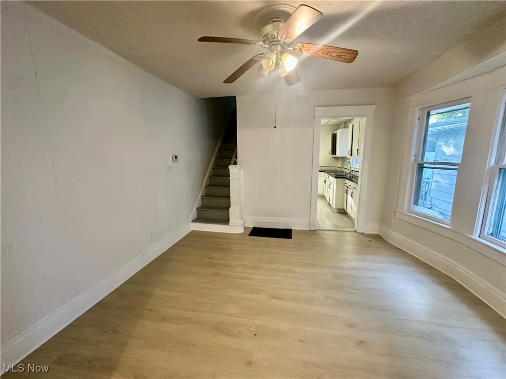 Unfurnished living room with light wood finished floors, stairway, ceiling fan, and a textured ceiling