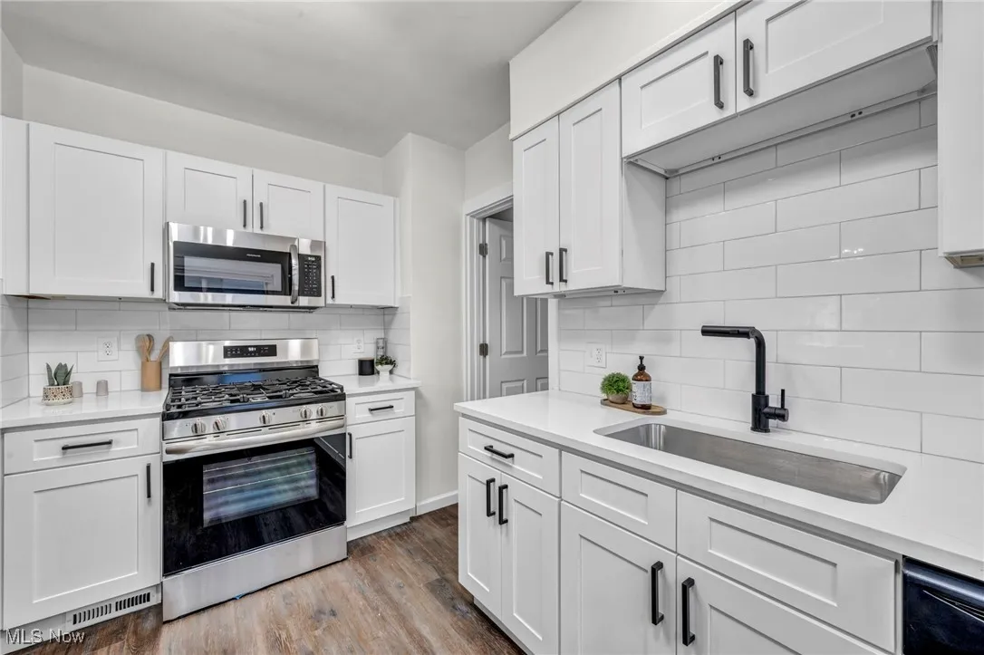 Kitchen featuring appliances with stainless steel finishes, tasteful backsplash, and white cabinets