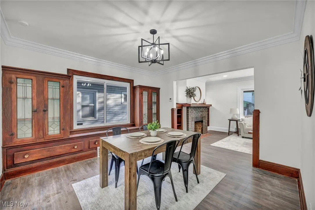 Dining room featuring ornamental molding, a fireplace, dark wood-style floors, and a chandelier