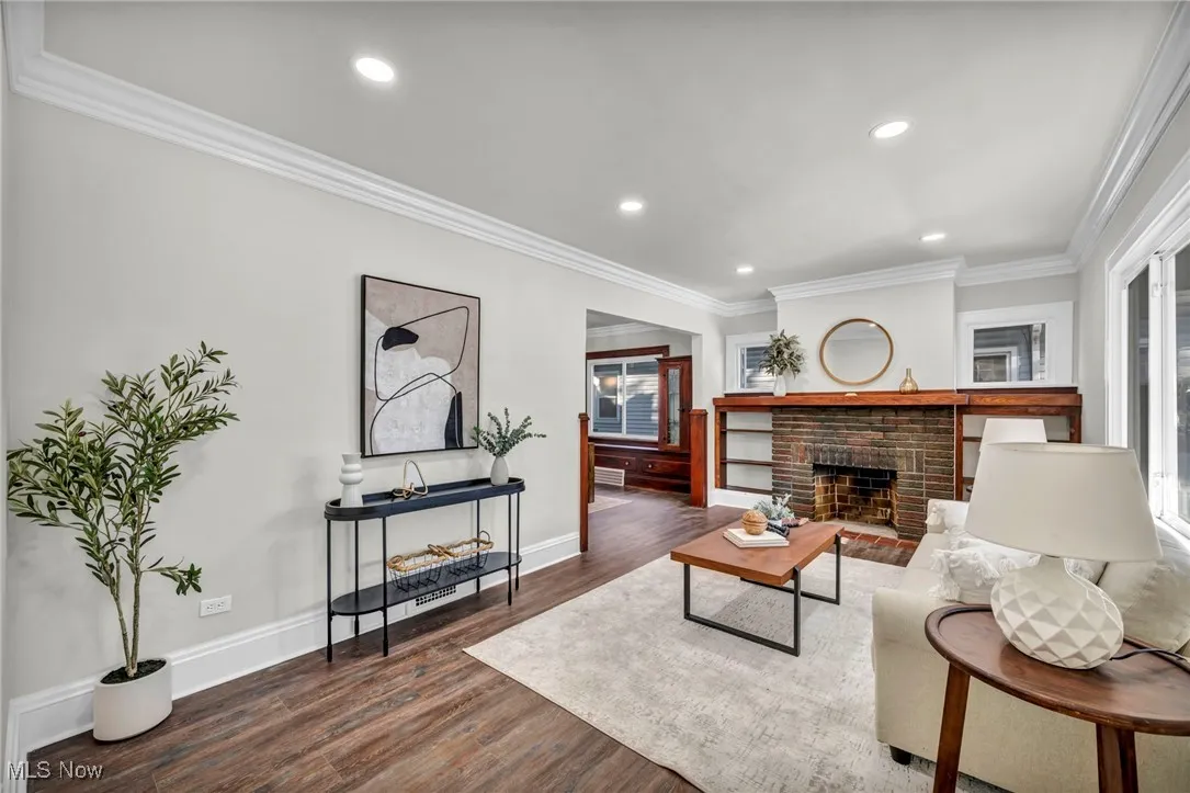 Living room featuring ornamental molding, a fireplace, dark wood-type flooring, and recessed lighting