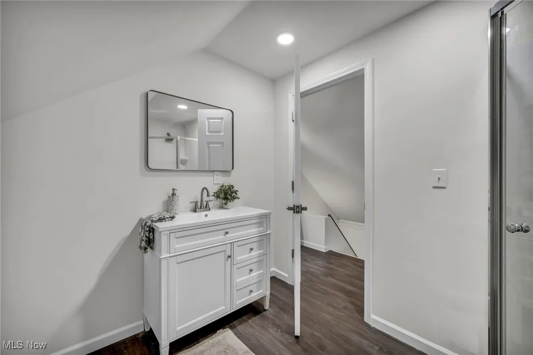 Bathroom featuring vanity, dark wood-style flooring, a shower with door, vaulted ceiling, and recessed lighting