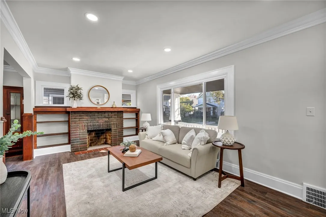Living room with ornamental molding, dark wood-type flooring, a fireplace, and recessed lighting