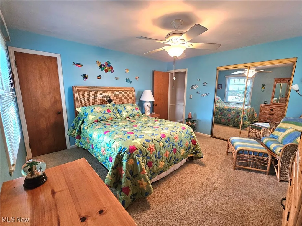 Carpeted bedroom featuring a ceiling fan and plenty of closet space