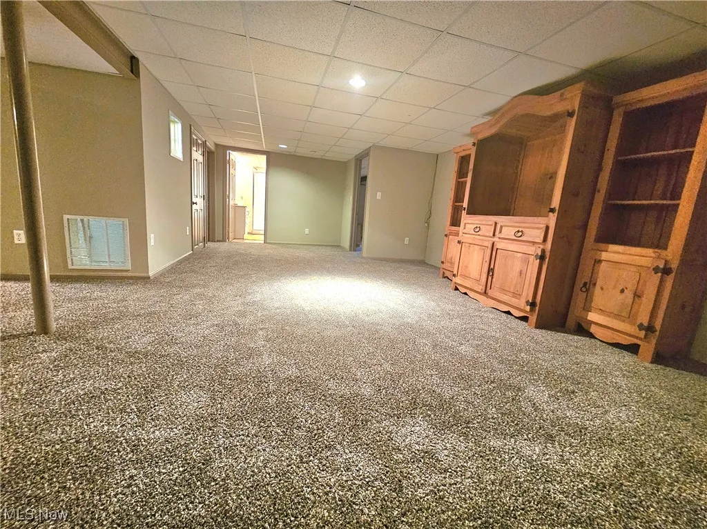 Unfurnished living room with carpet floors and a paneled ceiling
