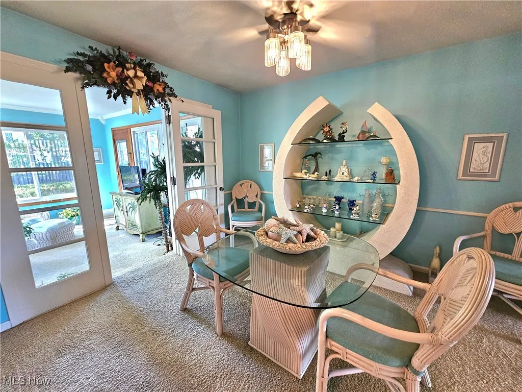 Dining room featuring carpet floors and a ceiling fan adjacent to sunroom