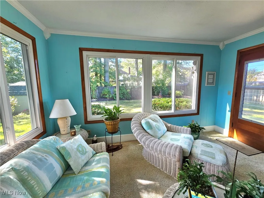 All season sunroom with ornamental molding, carpet, and healthy amount of natural light