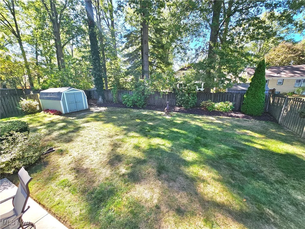 Fenced backyard featuring a shed