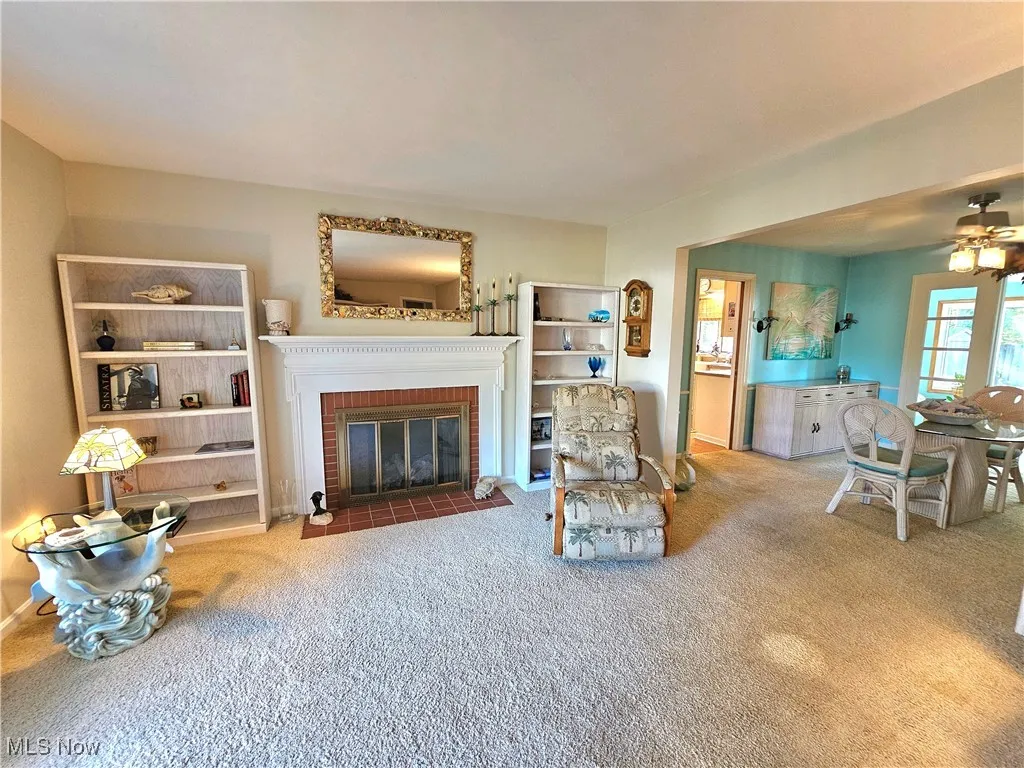 Carpeted living area featuring a fireplace adjacent to dining room