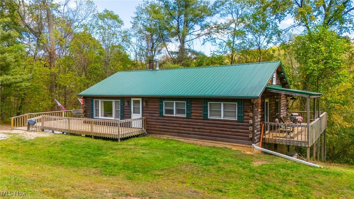 View of front of home featuring log siding, a metal roof, a front yard, and a deck