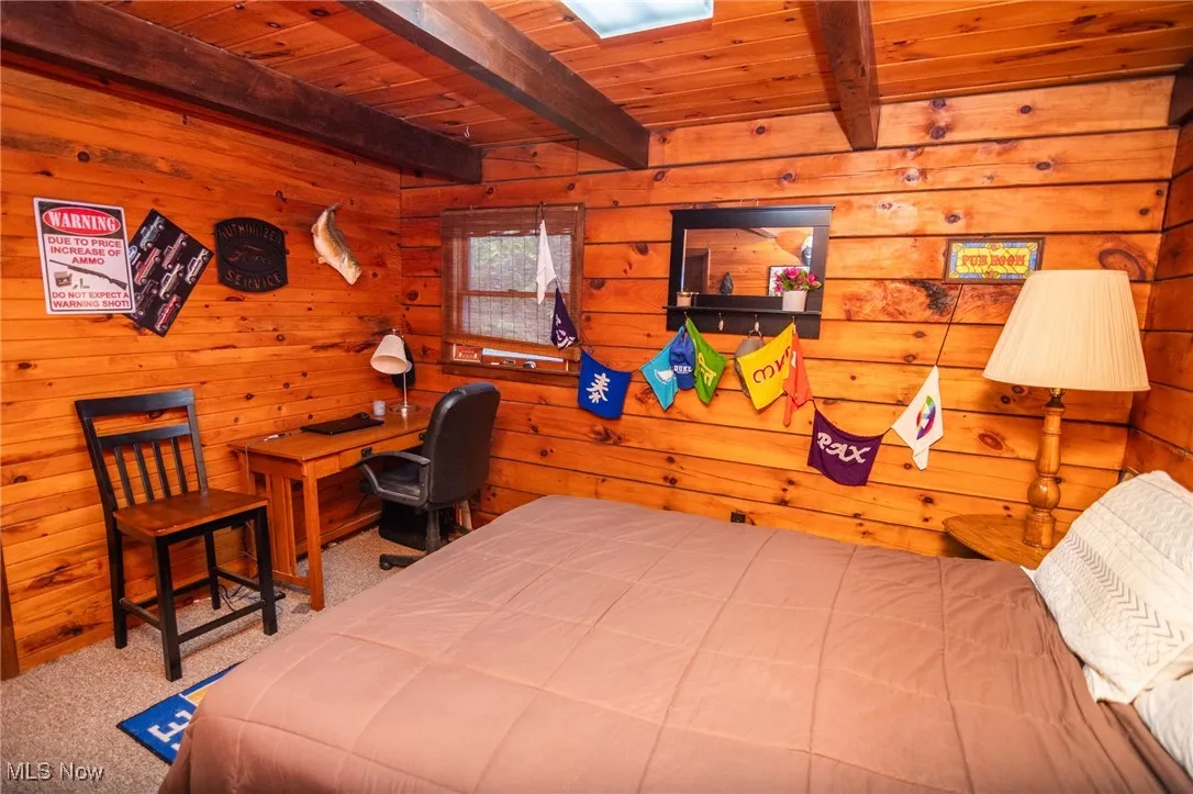 Carpeted bedroom featuring a wood ceiling with exposed beams and wood walls