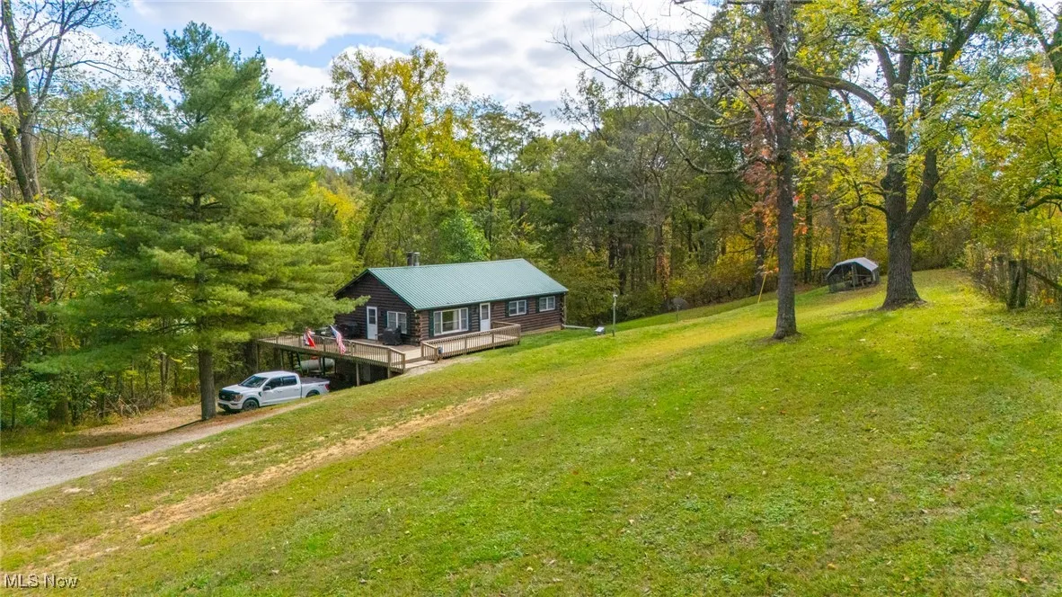 View of green lawn with driveway and a forest view