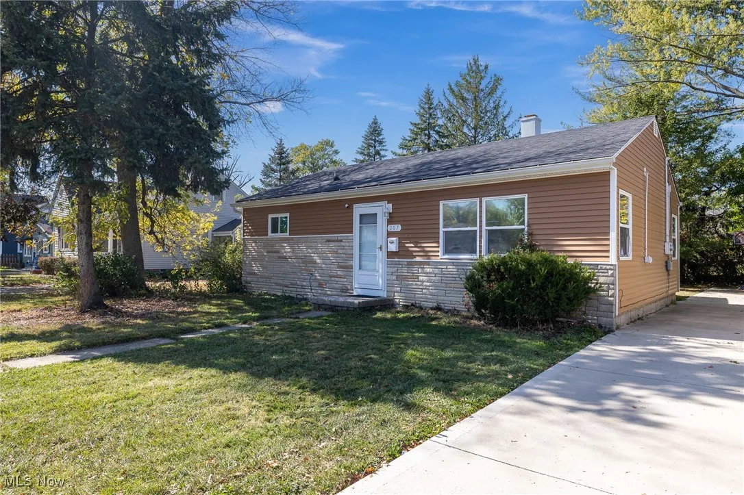 Bungalow-style house featuring a front lawn, a chimney, stone siding, and roof with shingles