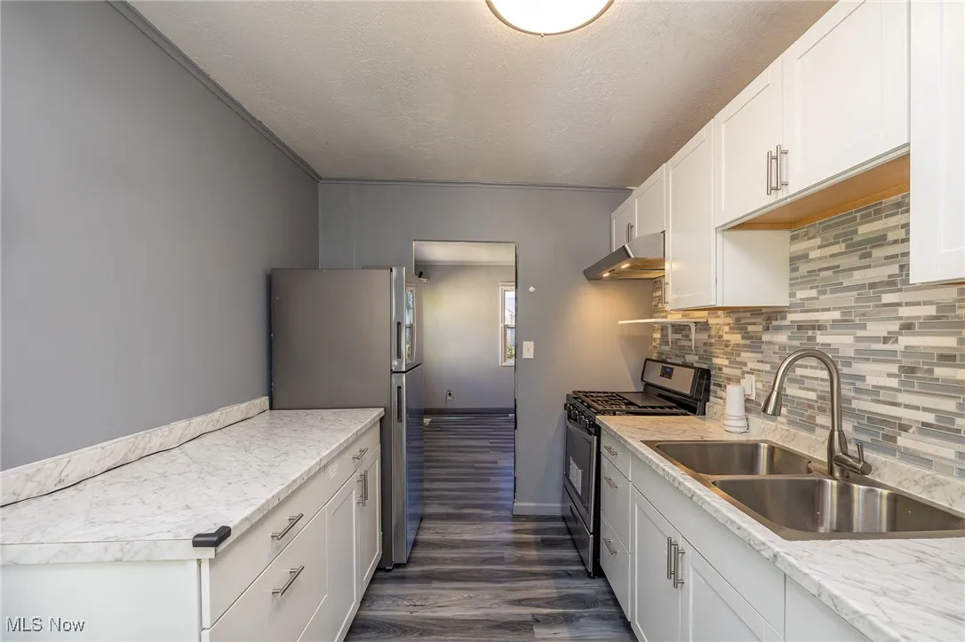 Kitchen with appliances with stainless steel finishes, white cabinetry, a textured ceiling, light countertops, and dark wood-style flooring