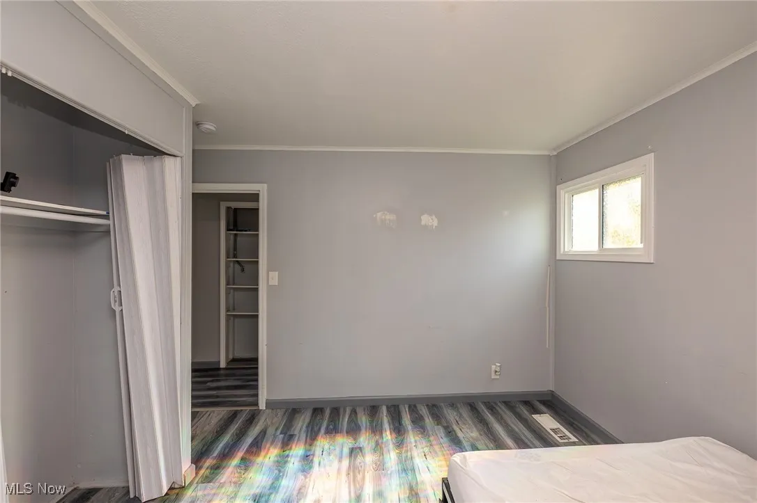Unfurnished bedroom with crown molding and wood finished floors