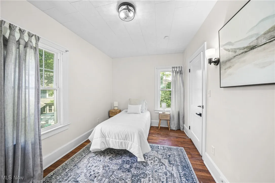 Bedroom with dark wood finished floors and baseboards
