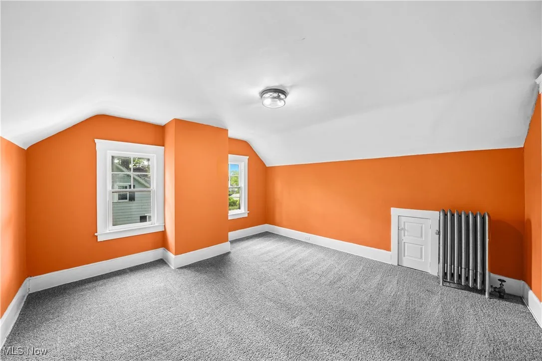 Bonus room with radiator, carpet, and vaulted ceiling