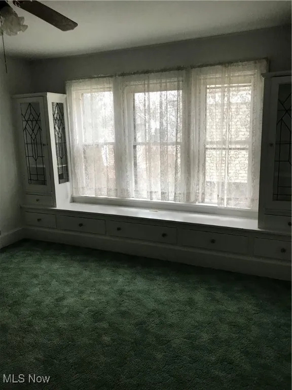 Empty room with dark carpet and ceiling fan