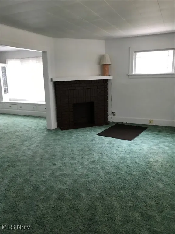 Unfurnished living room with carpet and a brick fireplace