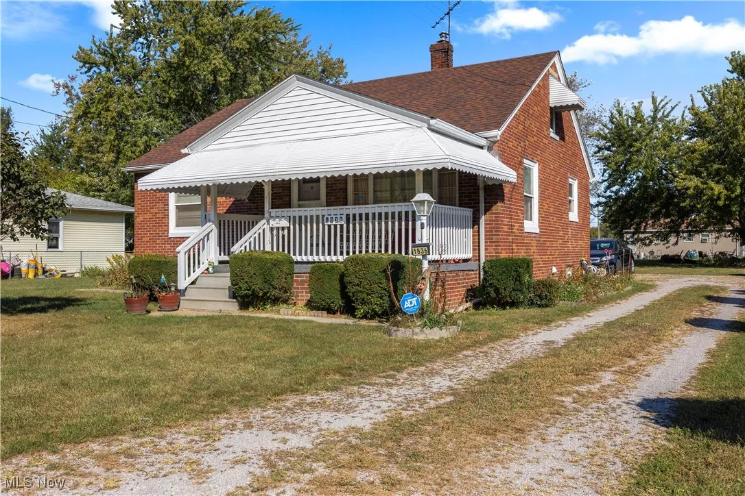 Bungalow with a porch, brick siding, a front yard, driveway, and roof with shingles