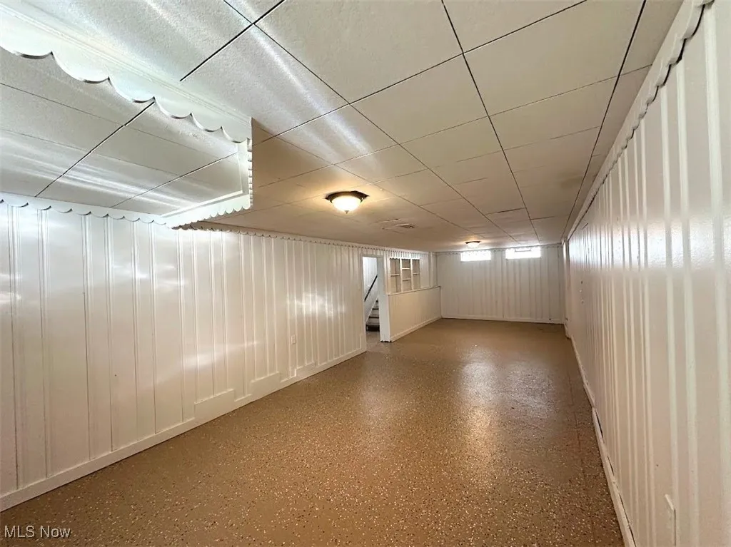 Empty room featuring stairs and a paneled ceiling