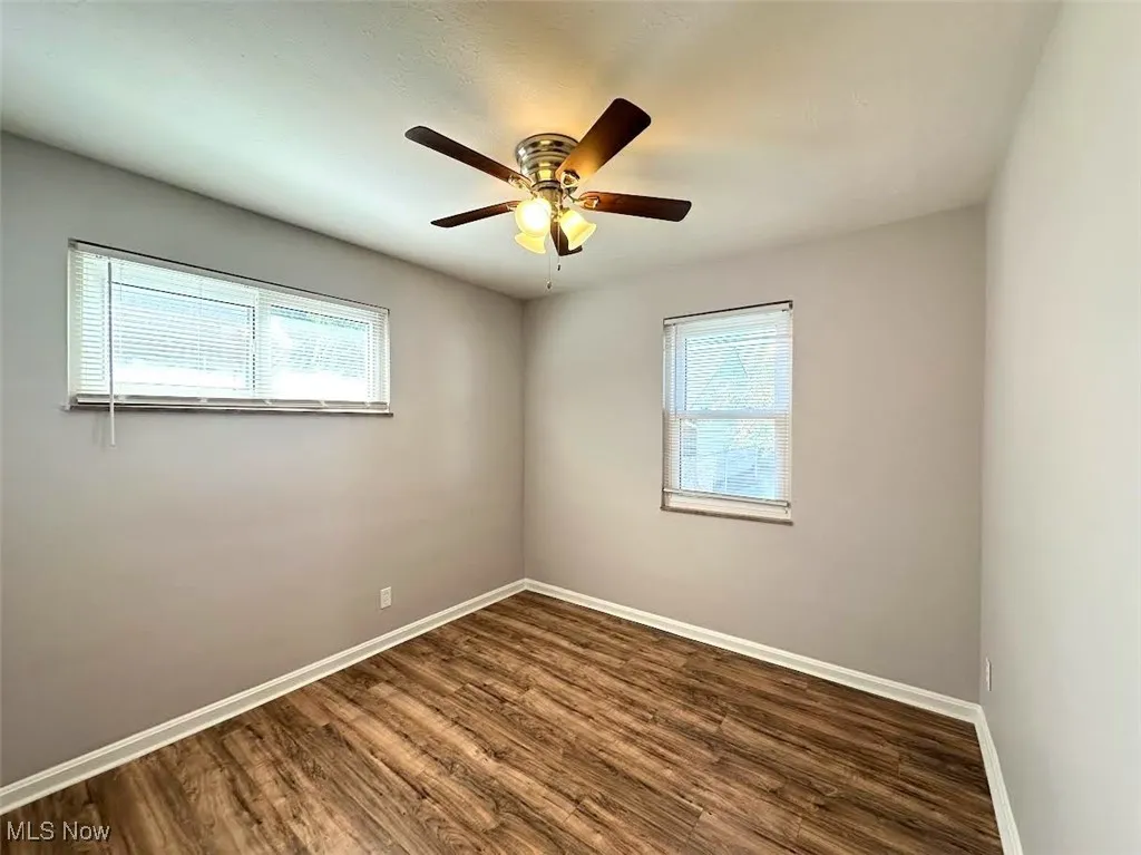 Empty room with dark wood-type flooring and a ceiling fan