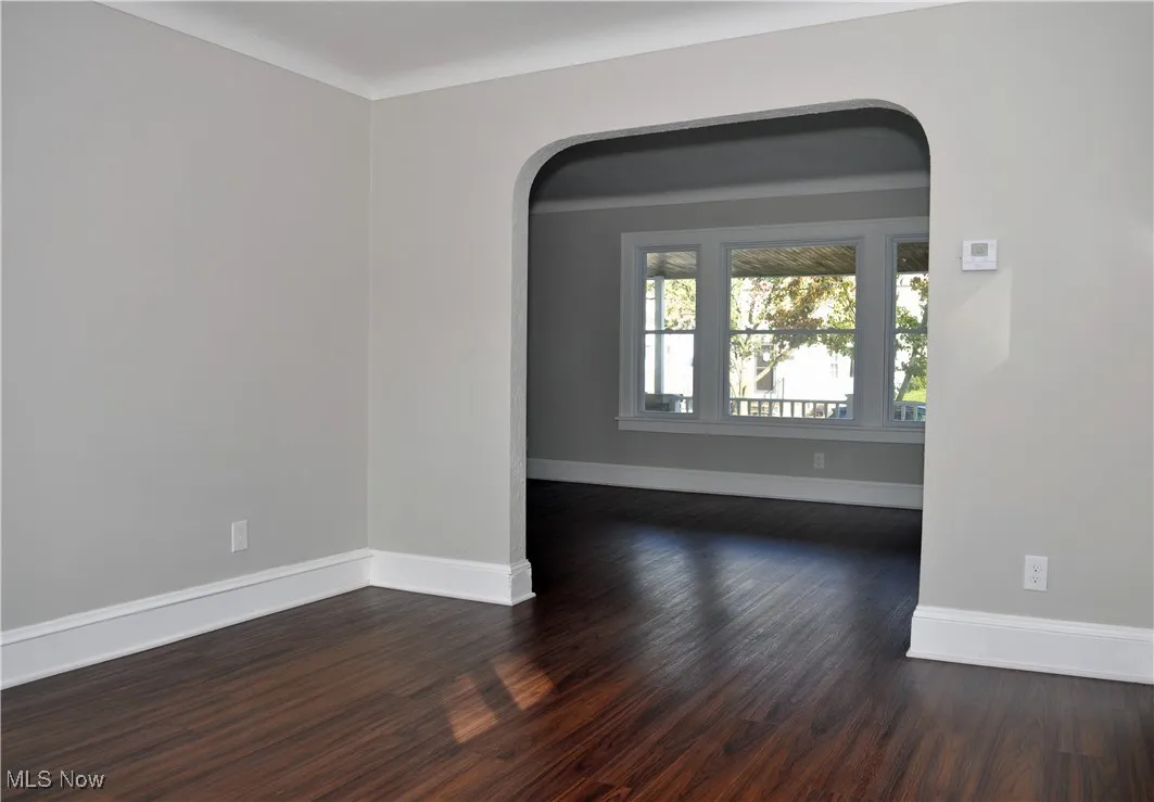 Empty room with dark wood-style floors and arched walkways