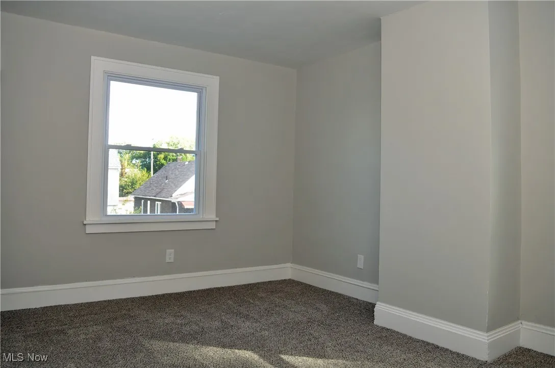 Carpeted spare room featuring baseboards
