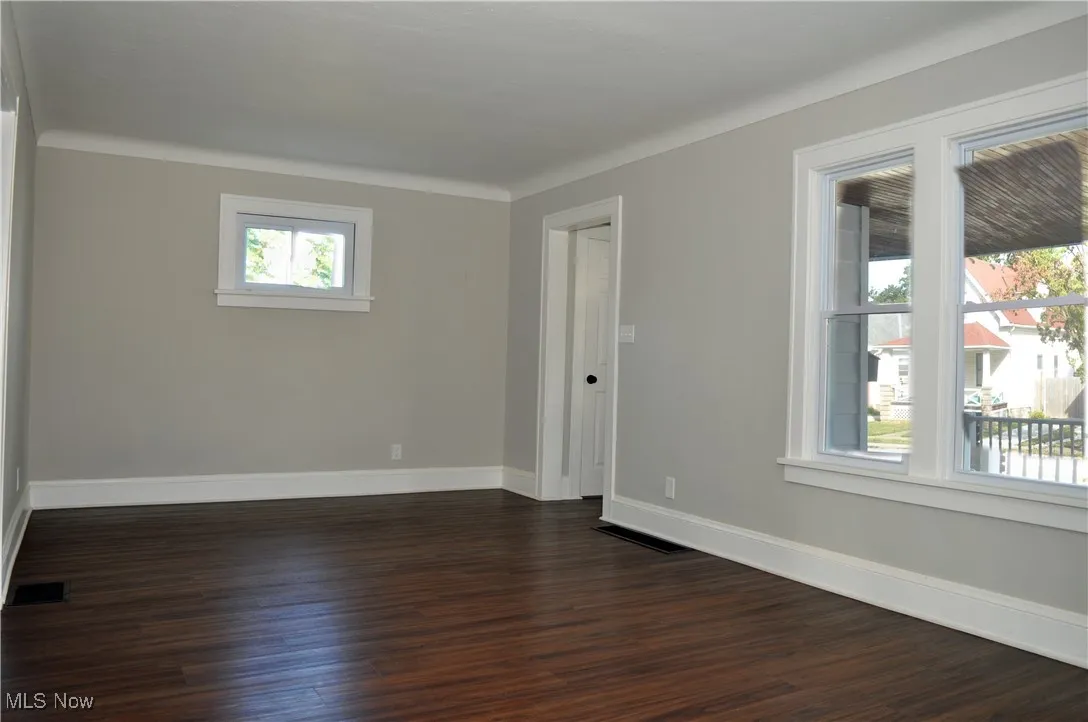 Spare room featuring baseboards and dark wood finished floors