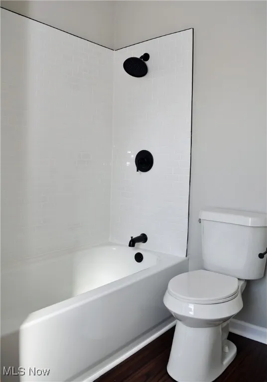 Bathroom with dark wood-style flooring and shower / washtub combination