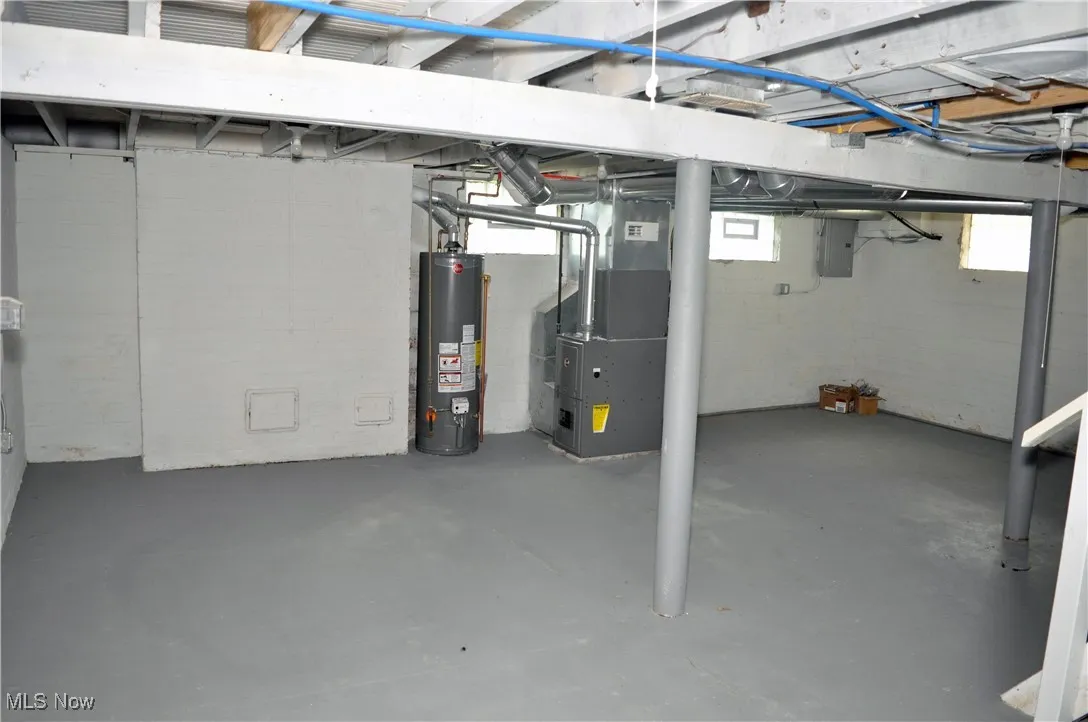 Below grade area featuring water heater, heating unit, and electric panel
