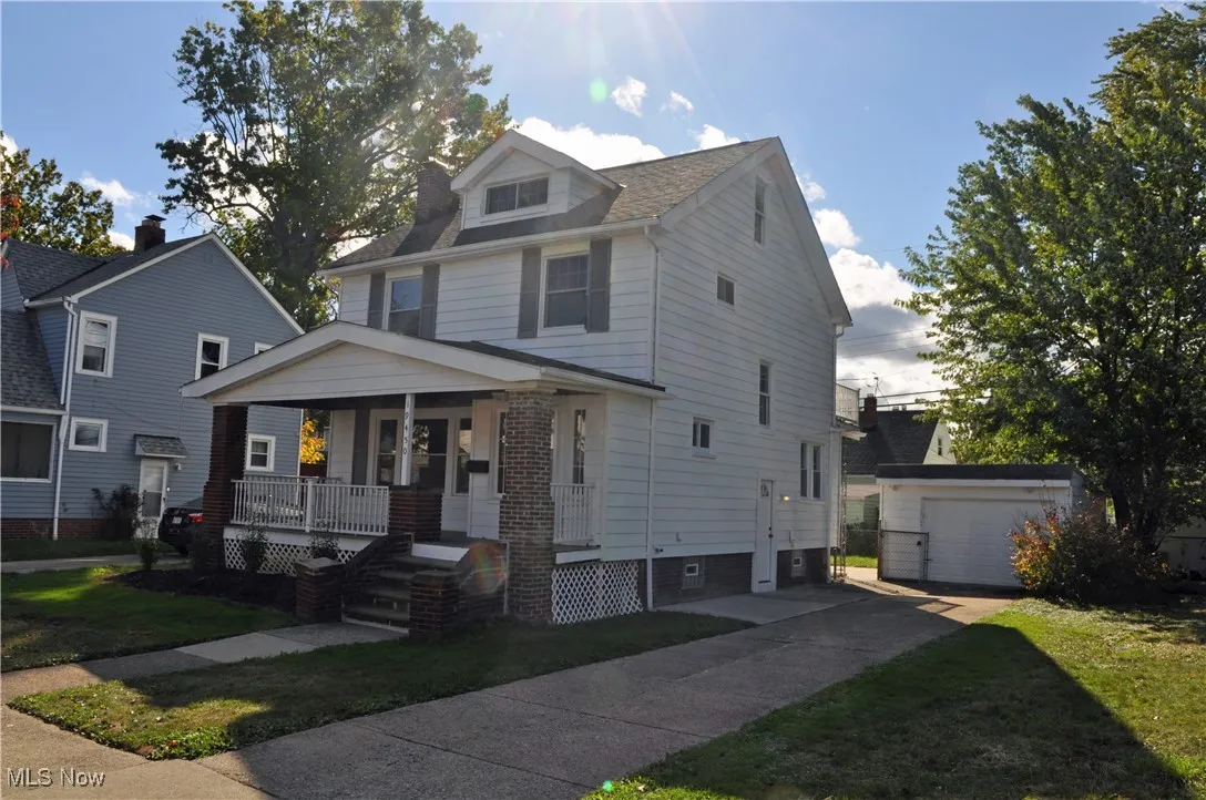 Traditional style home with covered porch, an outdoor structure, a front yard, and concrete driveway
