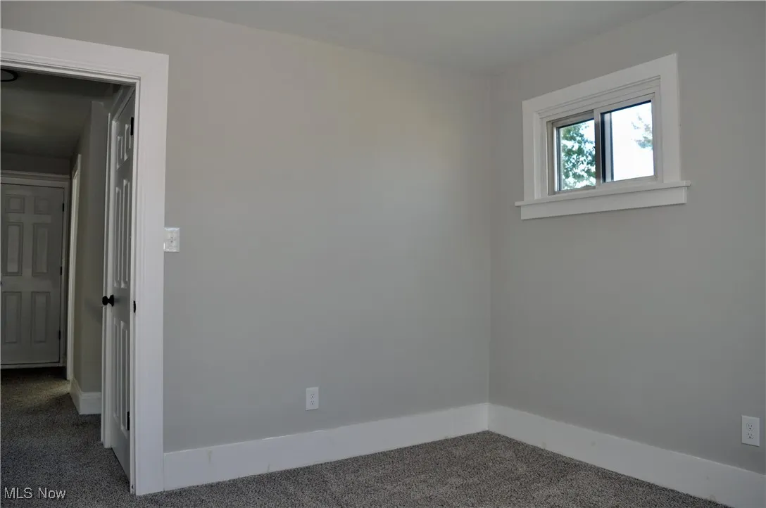 Spare room featuring carpet flooring and baseboards