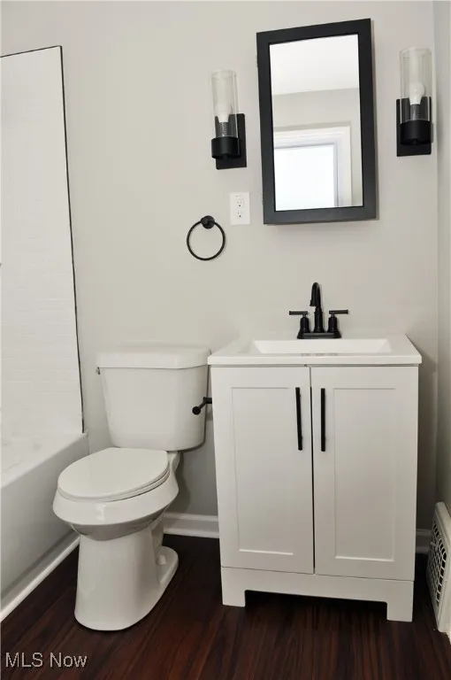 Full bath with vanity, dark wood-style flooring, and shower / tub combination