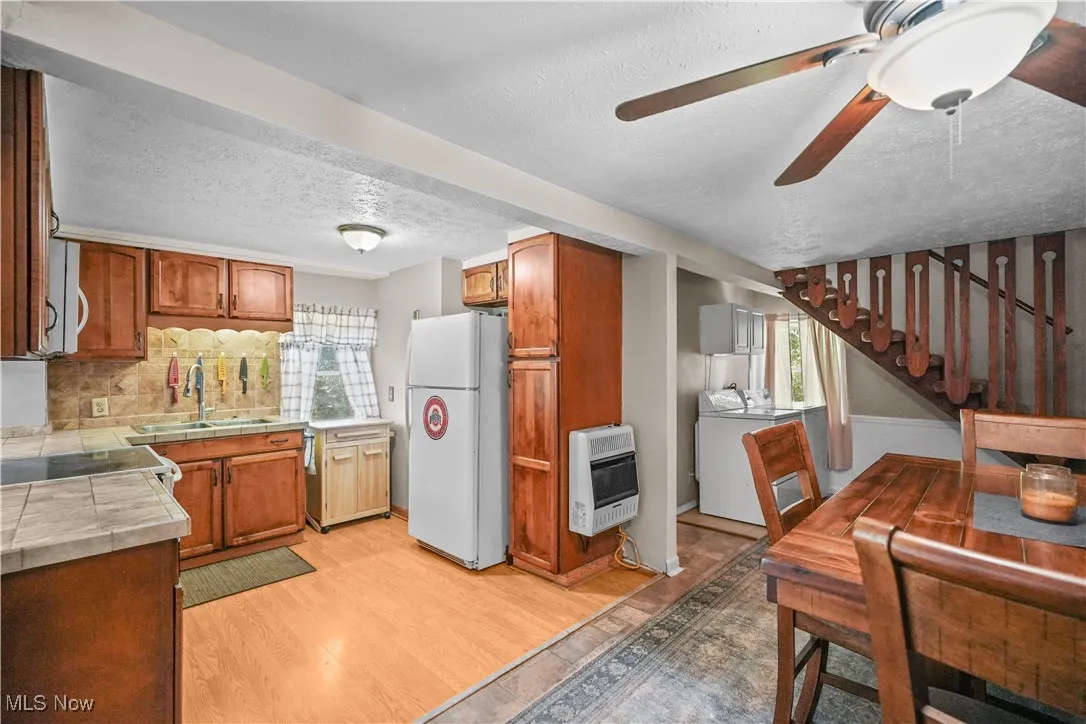 Kitchen featuring tile countertops, a textured ceiling, plenty of natural light, light wood-style floors, and white appliances